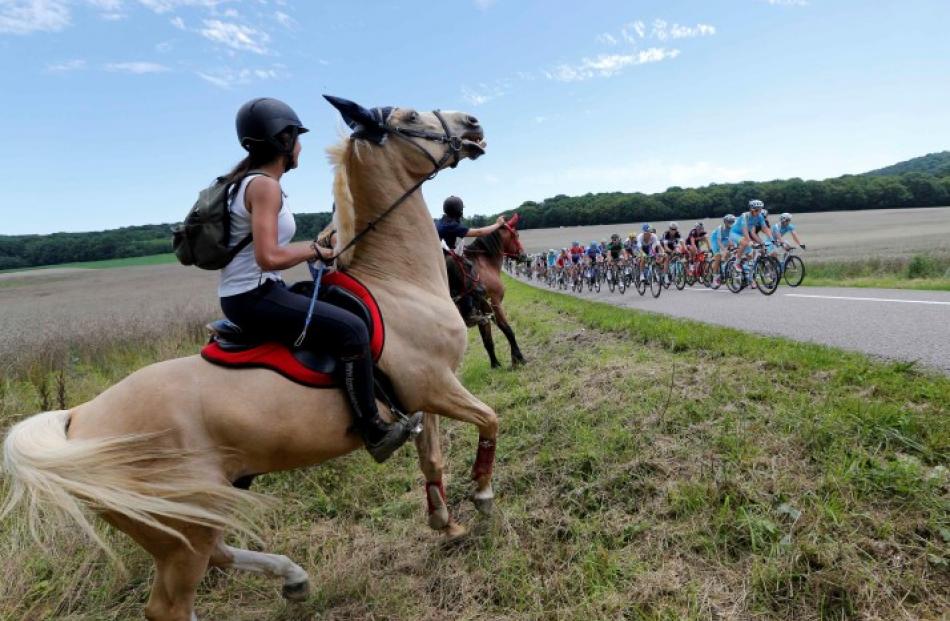 Horse riders watch as the pack of riders cycles on its way during the 187.5km 11th stage of the...