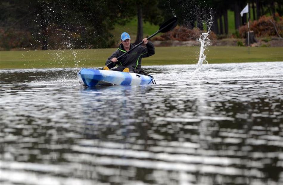 Island Park Golf Club greenkeeper Michael Minty kayaks up the fairway of the third hole yesterday...