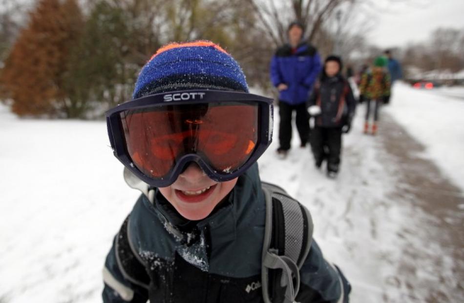 Jacob Rowell wears ski googles as he walks to school in Minneapolis after early snow hit parts of...