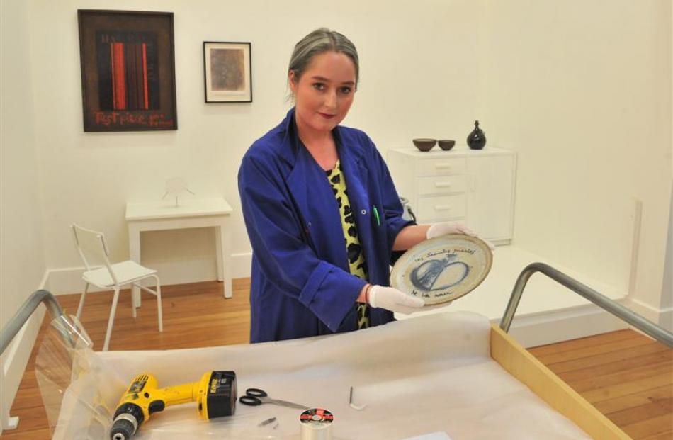 Jamie Metzger, a collection officer at the Otago Museum, holds a plate, painted by Dunedin artist...