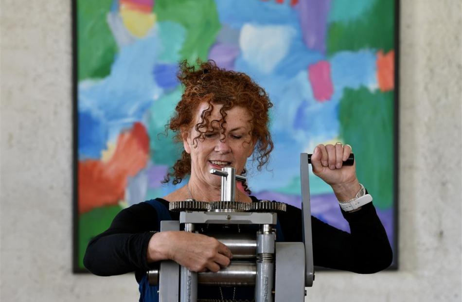 Jeweller Lynn Kelly works in her studio pressing silver on a rolling mill.  The work in the...