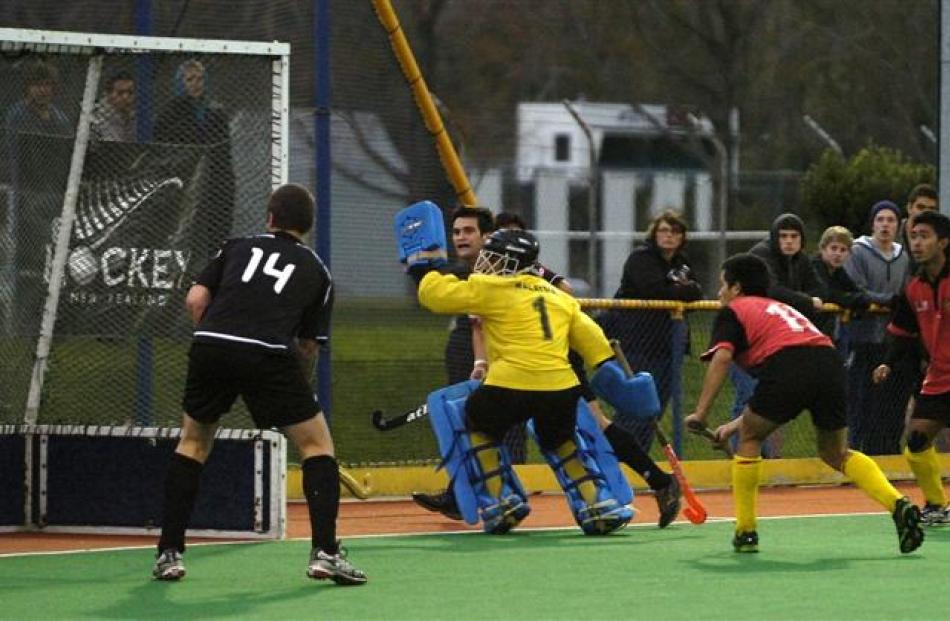 Junior Black Stick Nick Ross, partly obscured by Malaysian goalkeeper Hatizuddin, aims the ball...