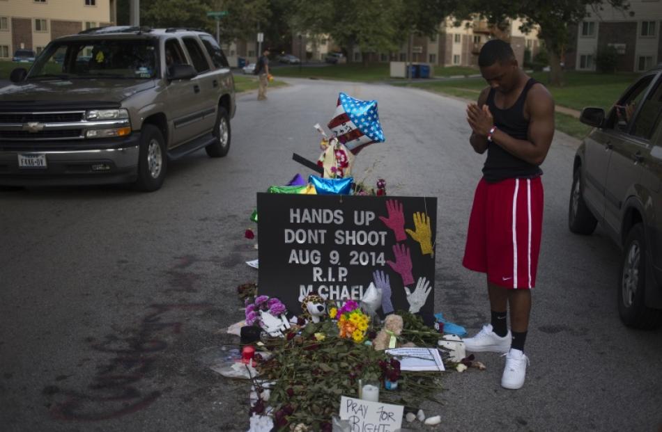 Ken Kendricks Jr., a nearby resident, puts his hands together in prayer at a makeshift memorial...