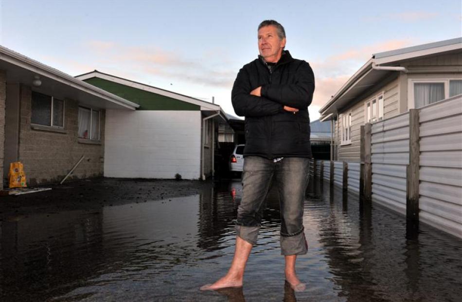 Kevin Foster surveys the floodwater outside his Burns St house. Photos by Gregor Richardson.