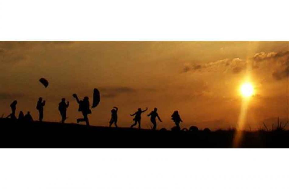 Kite fliers are silhouetted as the sun goes down on Hampstead Heath in London.