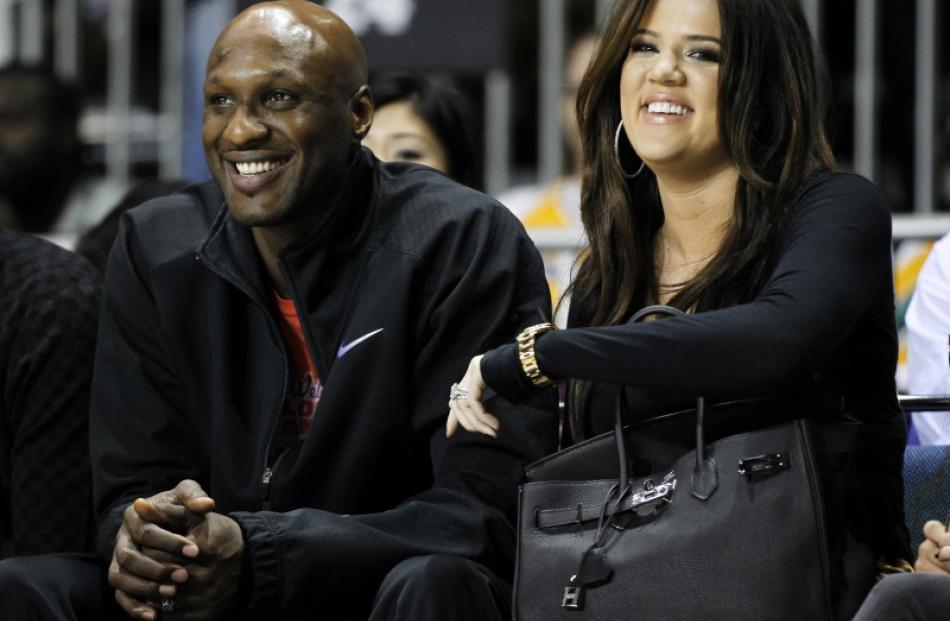 Lamar Odom and his wife television personality Khloe Kardashian sit courtside as they attend the...