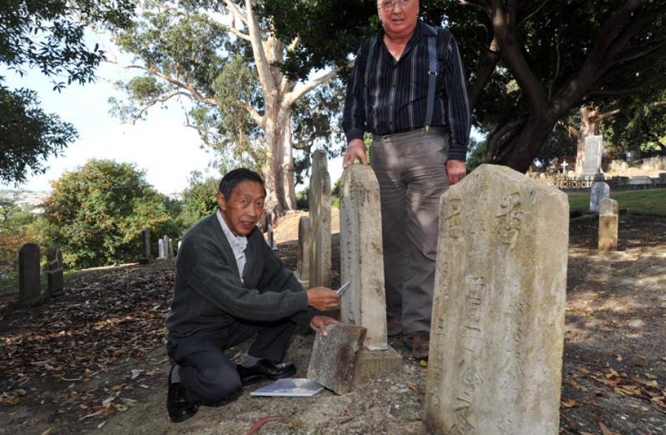 Leslie Wong (left) and Stewart Harvey inspect a restored headstone at the Southern Cemetery....