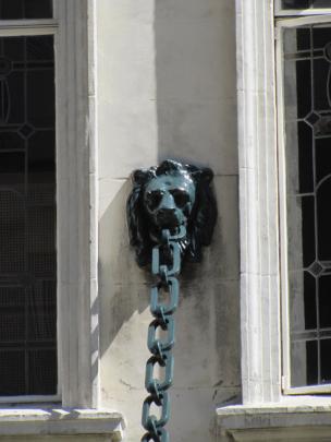 A lion's heads grasps an iron chain holding up a verandah.