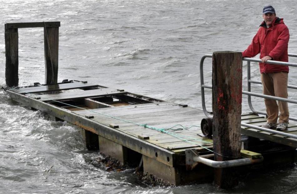 Macandrew Bay Boating Club treasurer Andy Edwards holds fast as the broken pontoon takes another...