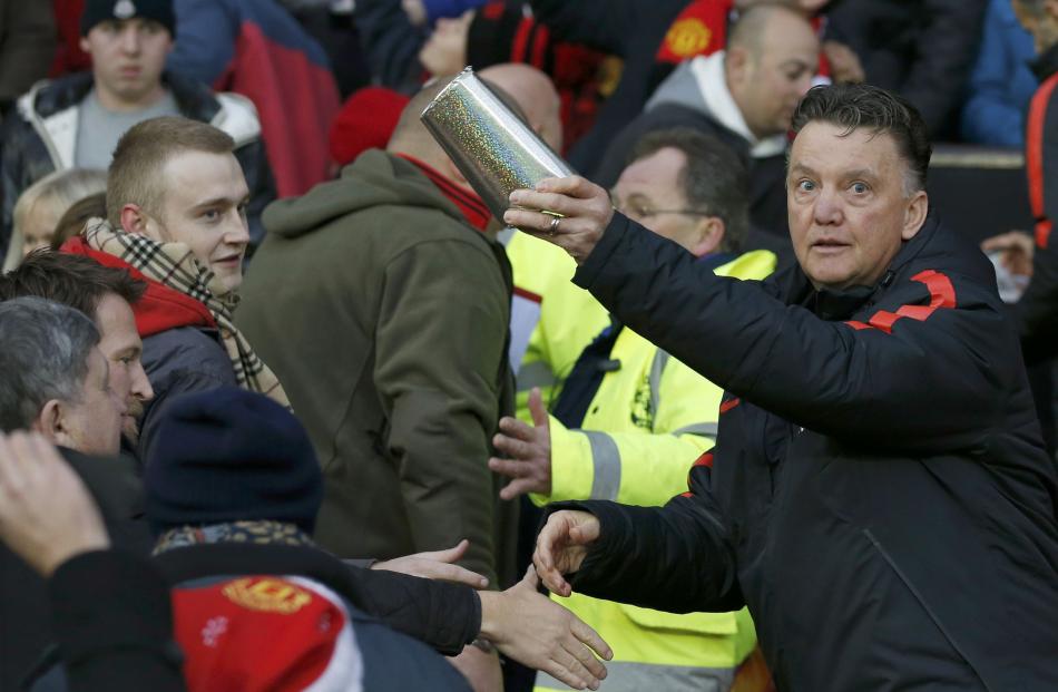 Manchester United manager Louis van Gaal hands out Christmas presents to fans before their...
