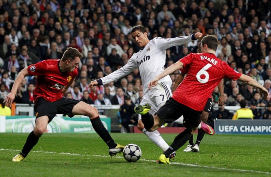 Manchester United's Phil Jones (L) and Jonny Evans stop Real Madrid's Cristiano Ronaldo from...