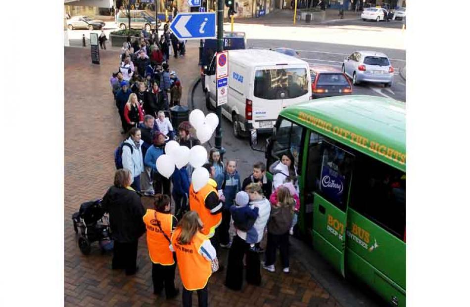 Members of the public queue to board buses going to the Baldwin St Jaffa Race at midday on Friday.