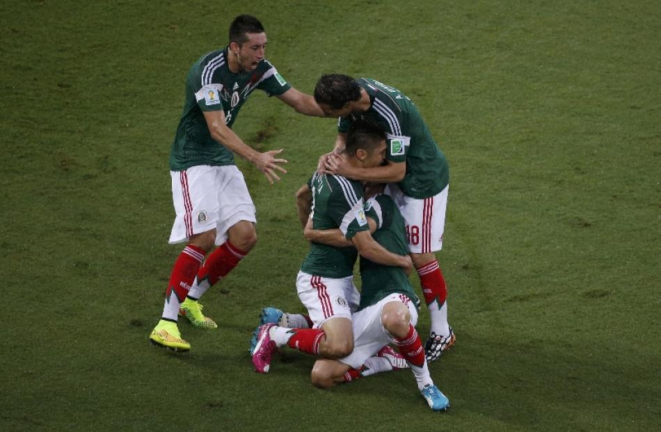 Mexico players celebrate after scoring against Cameroon during their 2014 World Cup Group A...