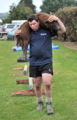 Michael Marshall, of West Otago, carries the carcass of a wild pig in the obstacle course section...