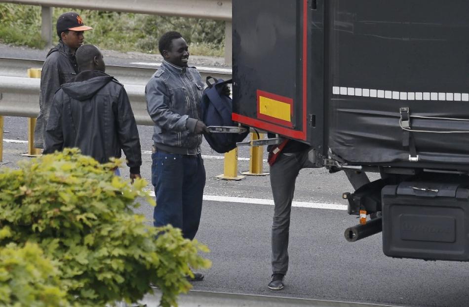 Migrants climb into the trailer of a truck during an attempt to make a clandestine crossing to...