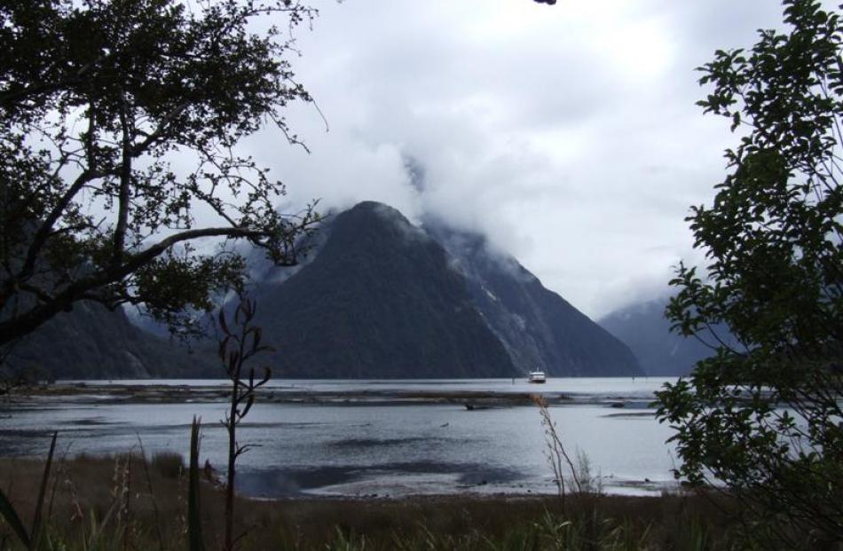 Mitre Peak hides its face behind a veil of cloud as a tourist vessel returns from an excursion on...