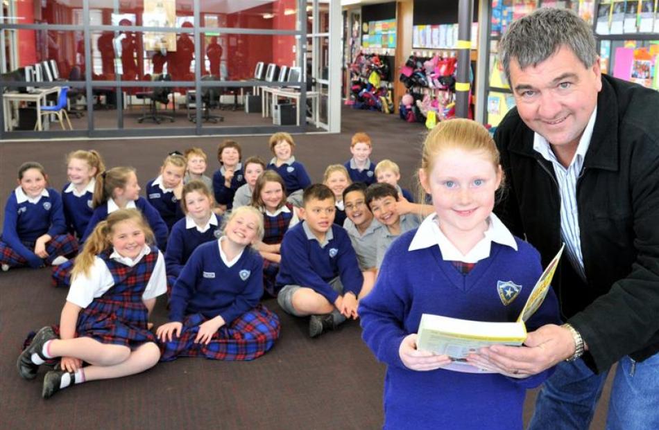 Mosgiel Rotary member Mike Lord gives the first dictionary to Nicole O'Brien (8) on Monday, while...