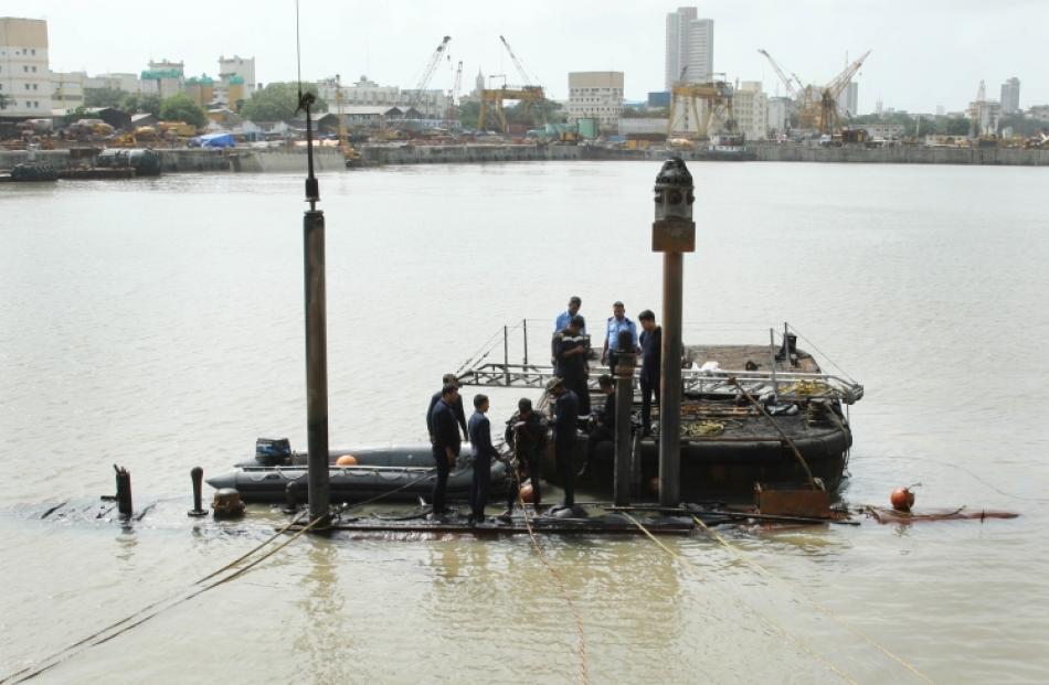 Navy divers standing on the INS Sindhurakshak submarine prepare to dive into the waters of the...