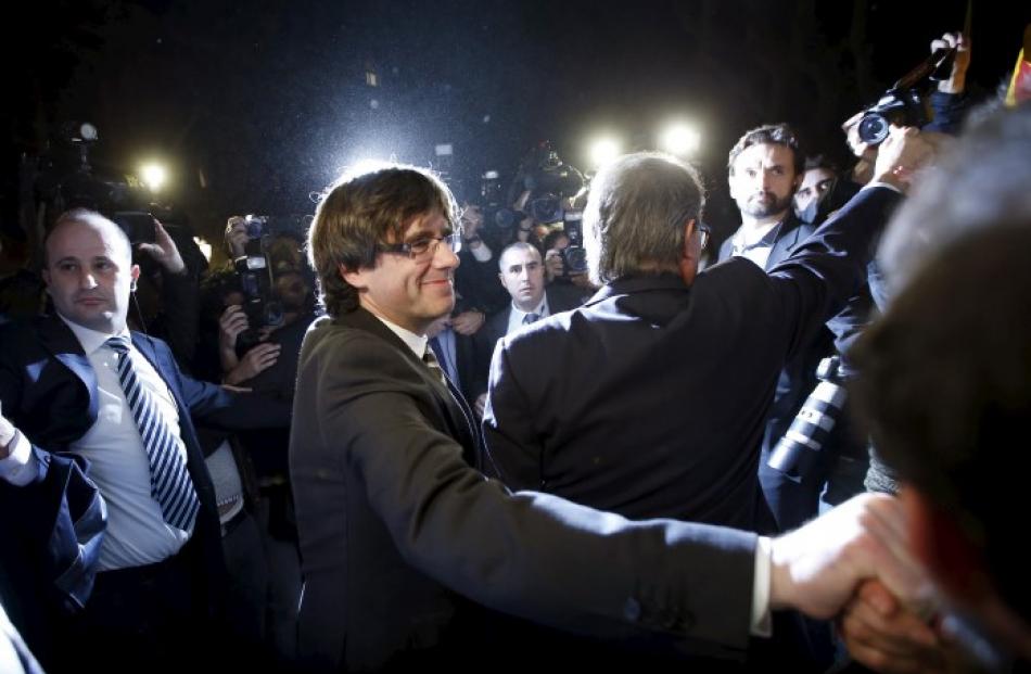 New Catalan President Carles Puigdemont (L) salutes supporters next to outgoing Catalan President...