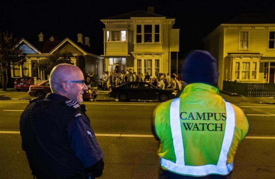 Noise control officer Rex Johnston stands with a campus watch officer in front of a student party...