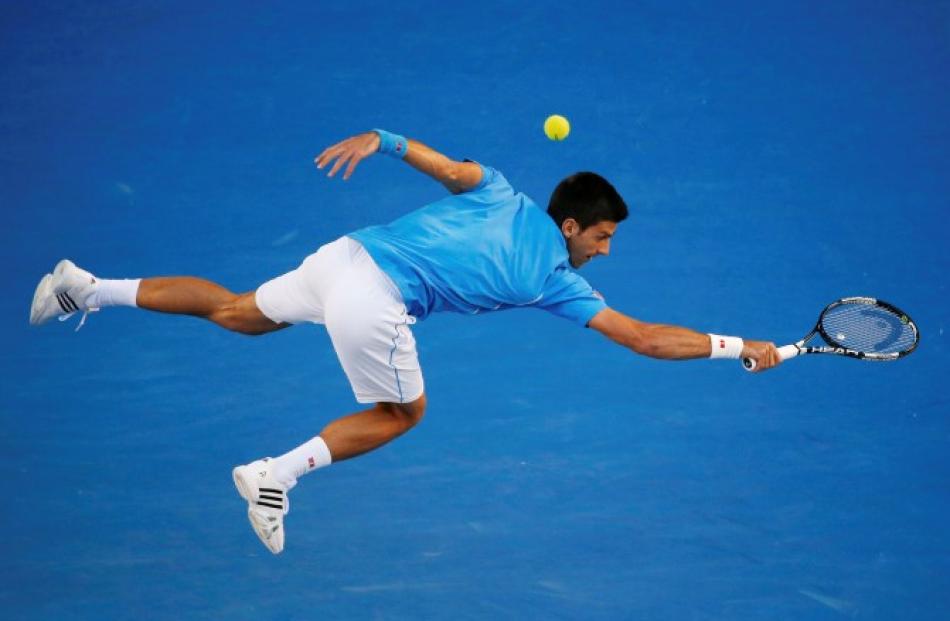 Novak Djokovic lunges to hit a return against Milos Raonic during their men's singles...