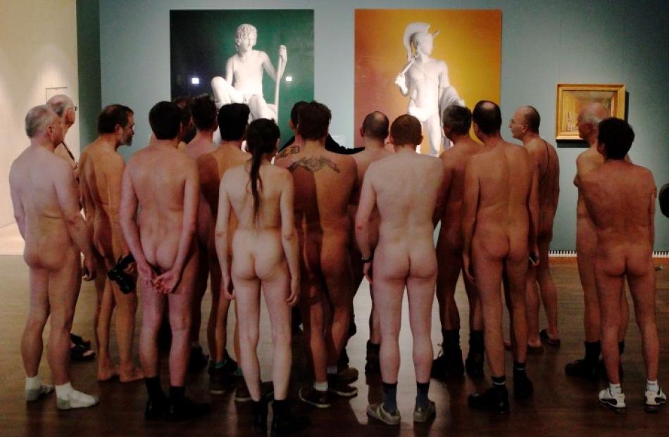 Nude visitors looks at the laserchrome prints 'Shepherd Boy' (L) and 'Jason' by Michael Elmgreen...