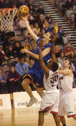 Nuggets swingman Matt Gillan makes a lay-up despite the attentions of Rams players Dennis Trammel...