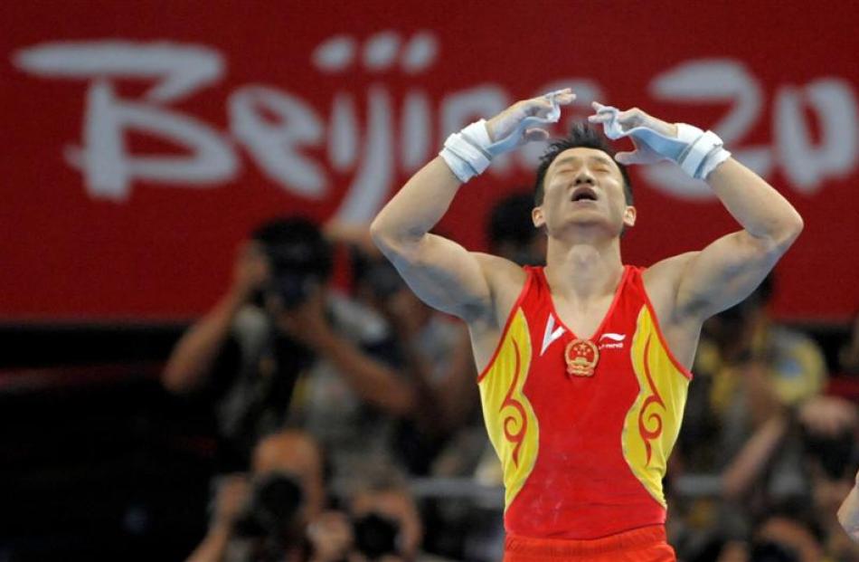 China's gymnast Yang Wei gestures after winning the gold medal in the Men's all-around...