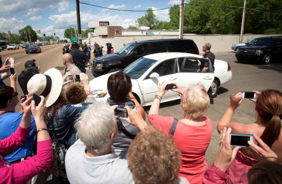 Onlookers take pictures of SUVs believed to carry Princes William and Harry as they depart Elvis...