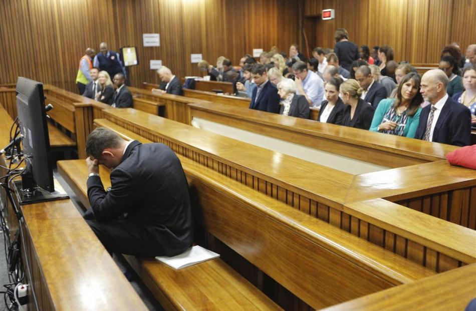 Oscar Pistorius clasped his head between his hands as lead defence lawyer Barry Roux read out...