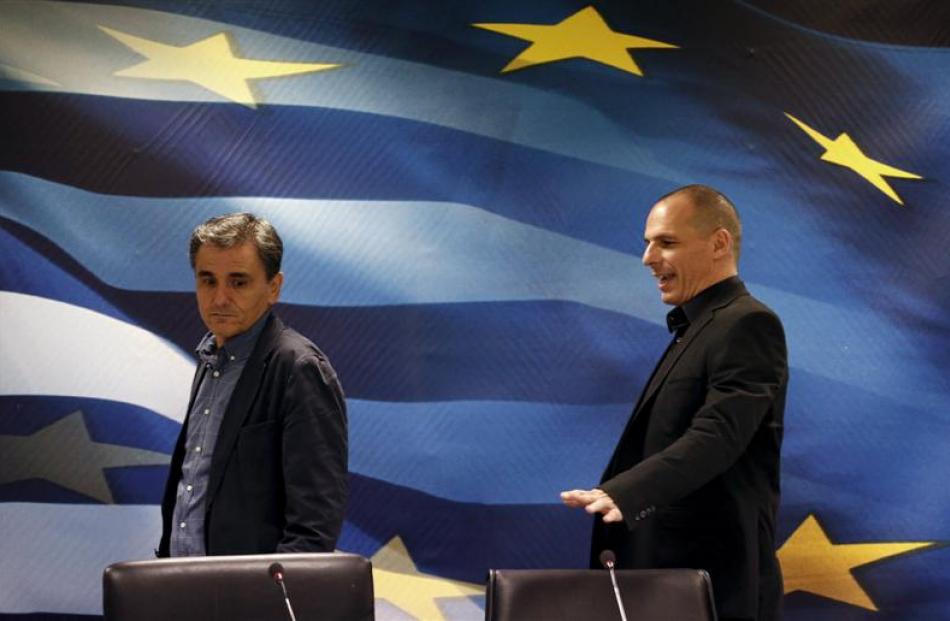 Outgoing Greek Finance Minister Yanis Varoufakis (right) shows newly appointed Finance Minister...