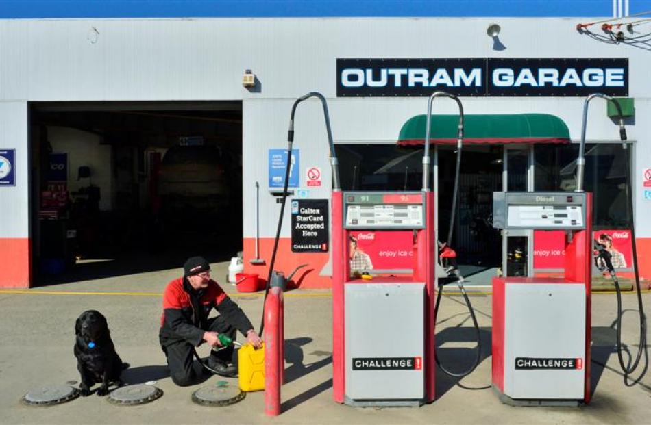 Outram Garage  owner-operator Ray Warnoch, who fills  a jerry can for a customer as his dog Tess...