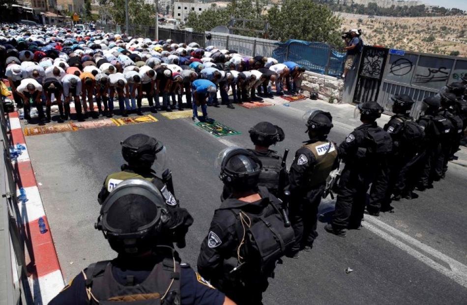 Palestinians pray on the first Friday of the holy month of Ramadan as Israeli policemen stand...