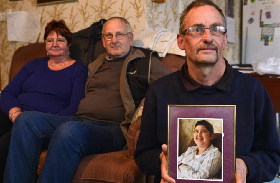 Parents Helen and Jim Christie are supporting their son-in-law Andy Ball, who holds a picture of...