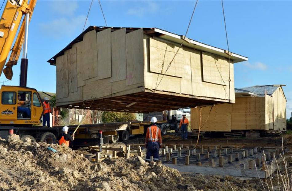 Patterson Contracting workers lower a house relocated from Christchurch's red zone on to its...