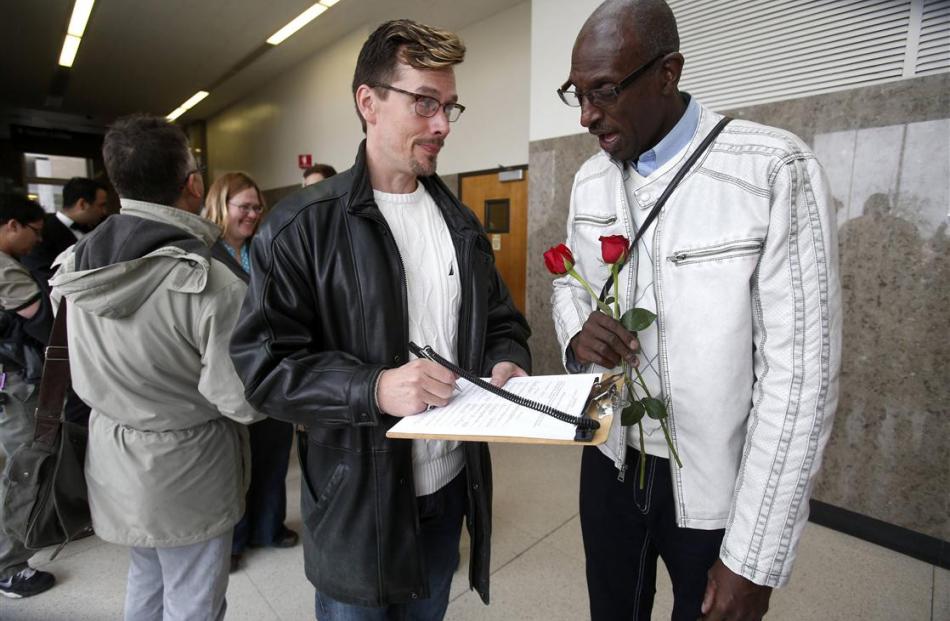 Paul Mattson and Roland Smith fill out paperwork as they stand in line for a marriage license at...