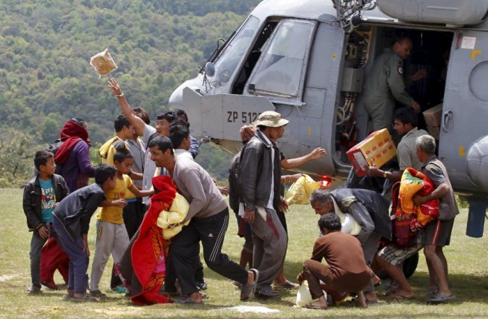 People collect relief material supplied by an Indian Air Force helicopter in a village affected...
