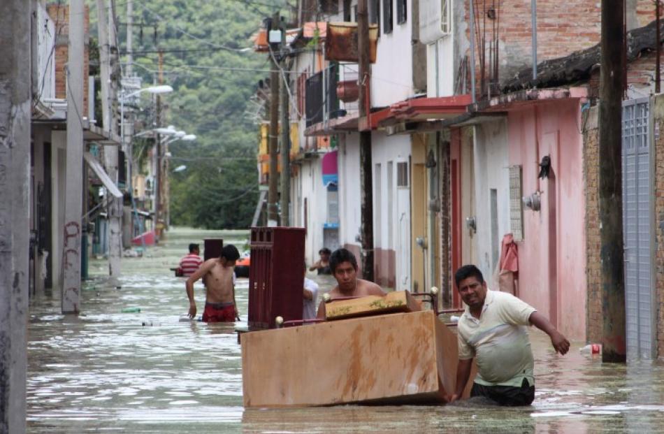 People move furniture through a flooded street in Tixtla, Mexico. REUTERS/Stringer