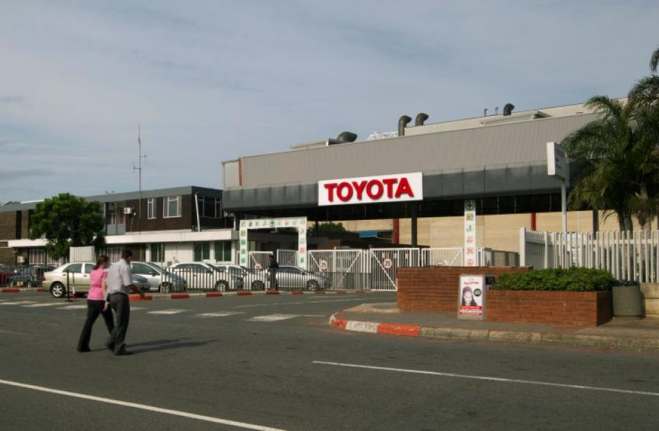 People walk near Toyota's Durban factory, which has been forced to shut down for four days due to...
