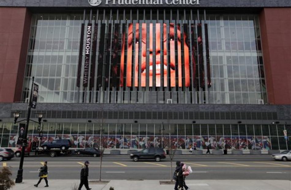 People walk past a large image of Whitney Houston displayed on the side of the Prudential Center...