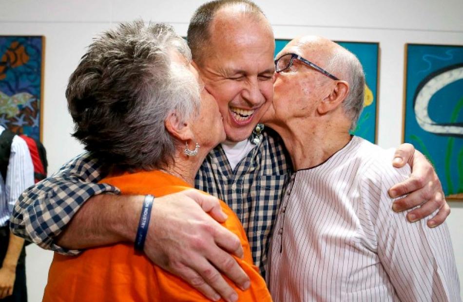 Peter Greste (C) receives a kiss from his mother Lois (L) and father Juris upon his return home...