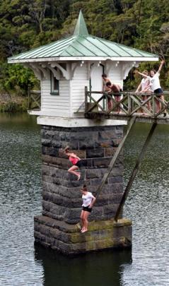 Teenagers leap from the bridge to the valve tower at Ross Creek Reservoir in Dunedin yesterday....