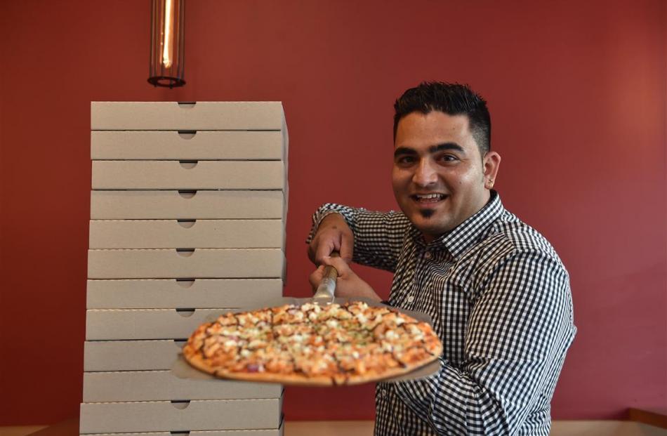 Pizza Bella owner Savi Arora serves a pizza in his George St store. Photos by Peter McIntosh.