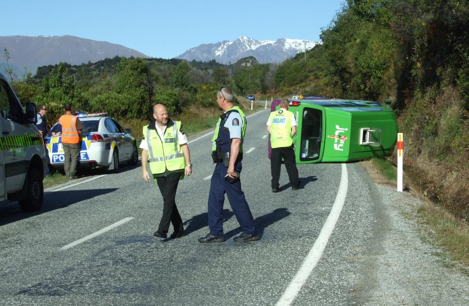 Police and ambulance staff inspect the site of a crash on the Queenstown-Glenorchy road this...