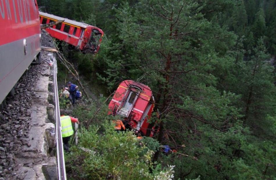 Police and rescue workers help after the train derailed into a ravine near Tiefencastel in a...