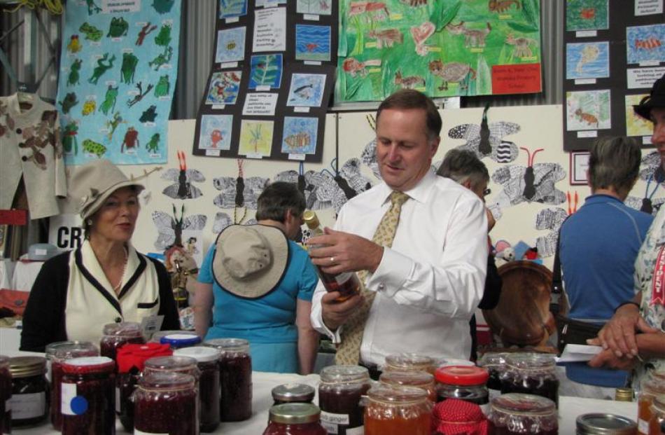 Prime Minister John Key admires a bottle of wine with Wanaka's Jan Allen (left) at the  home...