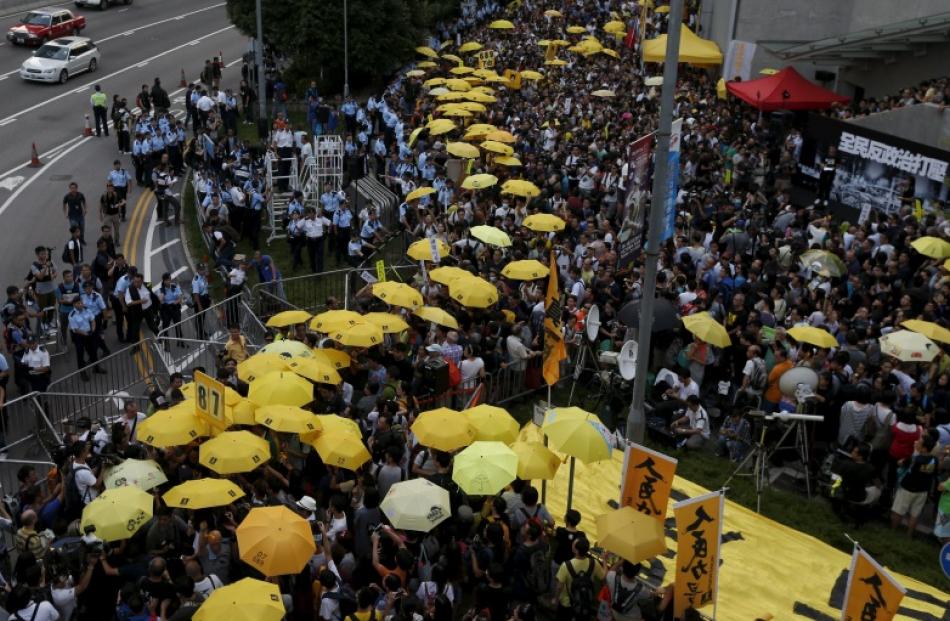 Pro-democracy protesters carrying yellow umbrellas, symbol of the Occupy Central movement, take...