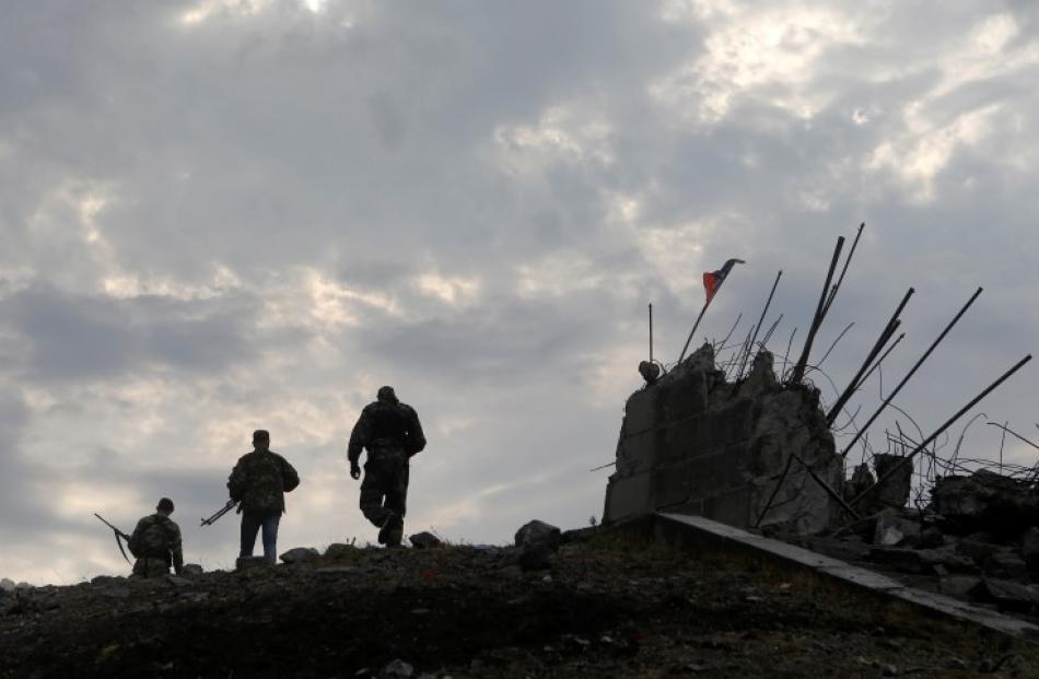 Pro-Russian separatists walk at a destroyed war memorial on Savur-Mohyla, a hill east of the city...