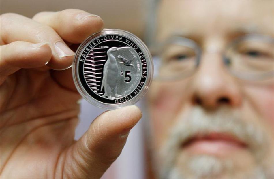 Prof Ewan Fordyce holds a 2014 collectable coin featuring the extinct giant Kairuku penguin....