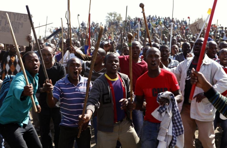 Protesters sing as they hold weapons outside a South African mine in Rustenburg, 100km northwest...